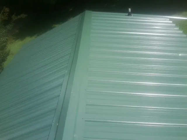 New green metal panels meeting at the ridge of a roof — Flat Roof Repair work by our crew in Coram