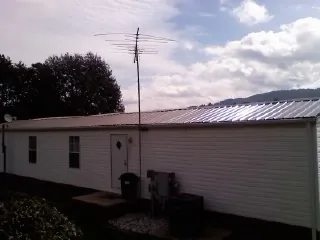 New metal roof on a single wide mobile home with a TV antenna in Coram