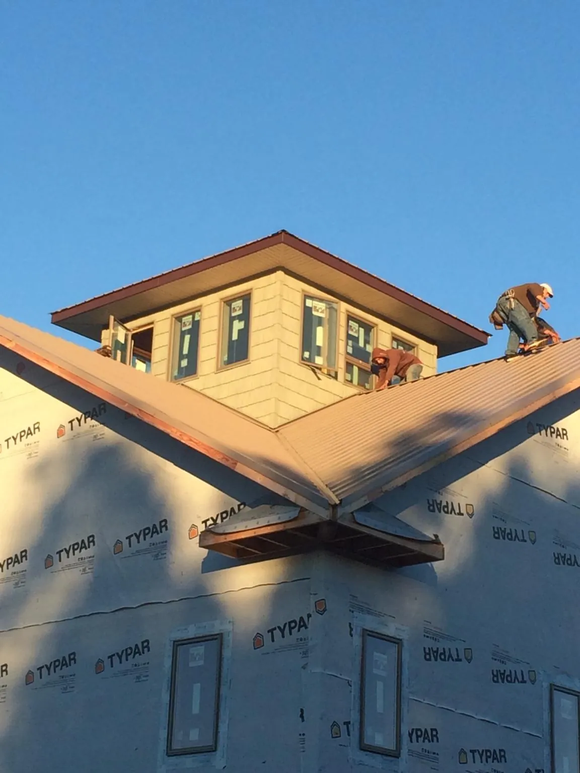 Roofers working around a rooftop cupola on a new metal roof at sunset — Roof Waterproofing in Coram by Roofing Brothers